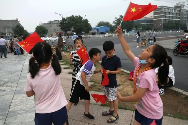 Children wave Chinese national flags on the street ahead of a rehearsal for the celebrations to mark the 100th founding anniversary of the Communist Party of China, in Beijing, China on June 26, 2021. (Photo by Tingshu Wang/Reuters)