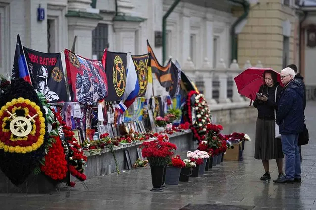A couple stand near an improvised memorial to Russian mercenary chief Yevgeny Prigozhin and others who died in a plane crash with him, on the 40 days their deaths, near the Kremlin, in Moscow, Russia, on Sunday, October 1, 2023. Prigozhin, the head of the Wagner military contractor, and nine other people, including his top associates, died when his private jet plummeted into a field northwest of Moscow shortly after taking off on Aug. 23. The authorities have remained silent about a possible cause of the crash. (Photo by Alexander Zemlianichenko/AP Photo)