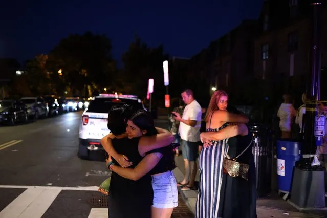 People embrace near the site of a shooting on July 22, 2021 in Washington, DC. Gunfire erupted on a busy street, injuring two and sending others fleeing for safety. A dark sedan was being sought in connection with the shooting and the two injured were expected to survive, according to published reports. (Photo by Anna Moneymaker/Getty Images)