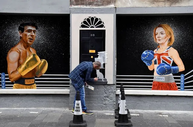 Artist Ciaran Gallagher finishes his mural depicting Britain's Conservative leadership candidate Rishi Sunak and British Foreign Secretary and Conservative leadership candidate Liz Truss, by painting Larry the cat, in the city centre of Belfast, Northern Ireland on August 17, 2022. (Photo by Clodagh Kilcoyne/Reuters)
