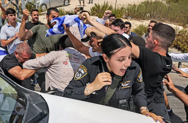 An Israeli policewoman calls out as behind her Israeli right-wing activists scuffle with a Palestinian man at the archaeological and religious site of the Tomb of Samuel at the Nabi Samuel village between Ramallah and Jerusalem in the occupied West Bank on September 2, 2022. (Photo by Ahmad Gharabli/AFP Photo)
