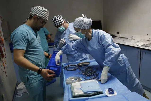 Head veterinary surgeon Hulya Hartoka (R) and veterinary surgeon Dursun Dogan (C) are helped by veterinary technician Gokhan Boyraz as they get ready for arthroscopic surgery to remove bone fragments from a racehorse at Veliefendi equine hospital in Istanbul April 6, 2015. (Photo by Murad Sezer/Reuters)