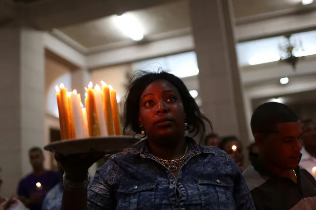 A worshiper holds candles inside the shrine of Saint Lazarus during the annual pilgrimage at the town of Rincon, Cuba, December 16, 2016. (Photo by Alexandre Meneghini/Reuters)