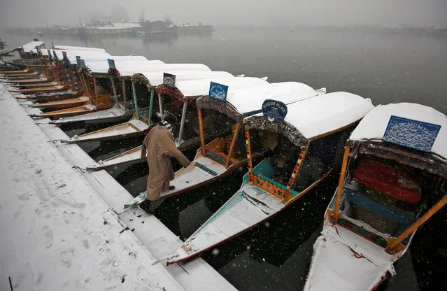 A man boards a boat on the banks of Dal lake during a snowfall in Srinagar January 16, 2019. (Photo by Danish Ismail/Reuters)