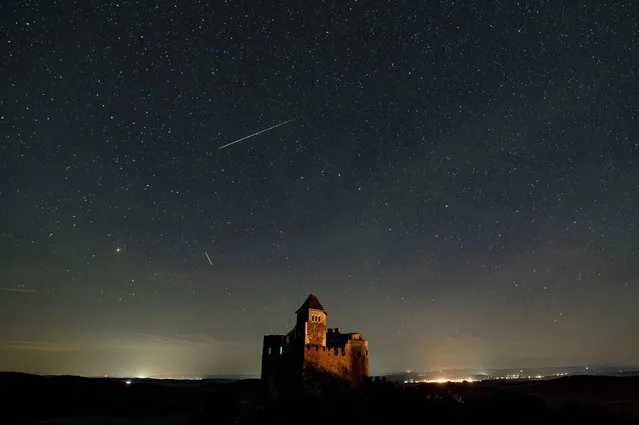 In this photo taken with long shutter speed, shooting stars are seen during the Perseids meteor shower above the castle of Holloko, Hungary, early 13 August 2023. The Perseid meteor shower occurs every year in August when the Earth passes through debris and dust of the Swift-Tuttle comet. (Photo by Peter Komka/EPA/EFE)