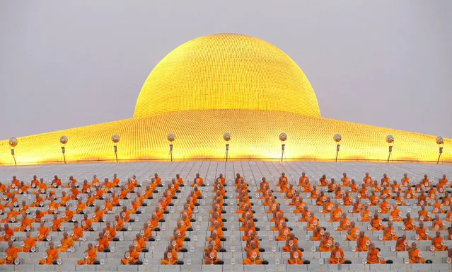 Thai Buddhist monks holding an alms bowl (C, front) walks in front of meditating fellow monks ahead of the morning alms offering ceremony to mark the Makha Bucha day at Wat Phra Dhammakaya temple in Pathum Thani province, on the outskirts of Bangkok, Thailand, 22 February 2016. Makha Bucha, known as the day of the Fourfold Assembly, is one of the holiest days to commemorate on the full moon night of the third lunar month the day that Lord Buddha gave the first sermon on the essence of Buddhism to his ordained 1,250 monk disciples assembled all by spontaneously gathered without an appointment. (Photo by Rungroj Yongrit/EPA)