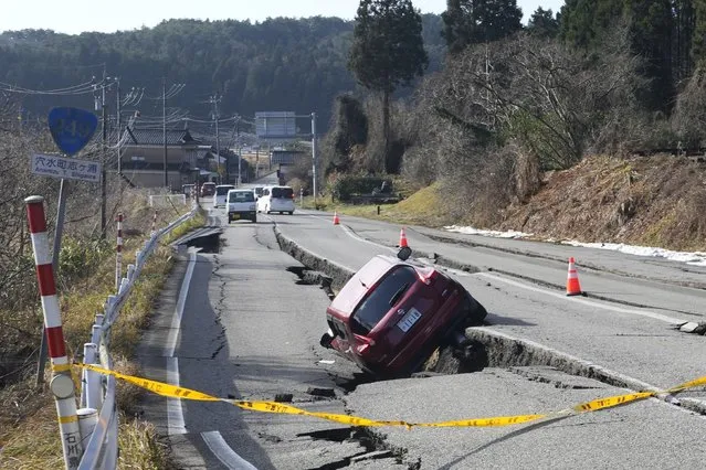 A car is trapped at a partially collapsed road caused by a powerful earthquake near Anamizu Town, Ishikawa Prefecture Tuesday, January 2, 2024. A series of powerful earthquakes hit western Japan, damaging buildings, vehicles and boats, with officials warning people in some areas on Tuesday to stay away from their homes because of a risk of more strong quakes. (Photo by Hiro Komae/AP Photo)