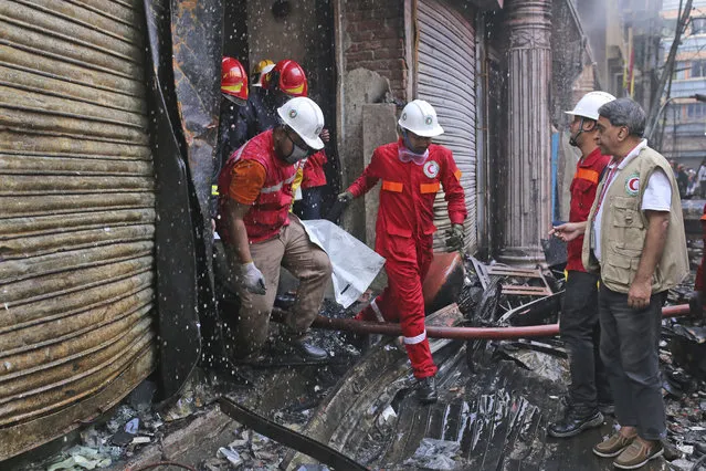 Firefighters retrieve a body from the site of a fire that broke out late Wednesday in closely set buildings in Dhaka, Bangladesh, Thursday, February 21, 2019. A devastating fire raced through at least five buildings in an old part of Bangladesh's capital and killed scores of people. (Photo by Rehman Asad/AP Photo)