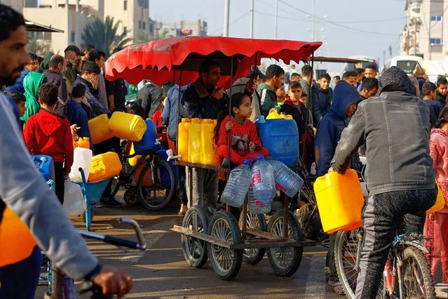 Palestinian children and youth wait to collect drinking water, amid shortages of drinking water, as the conflict between Israel and the Palestinian Islamist group Hamas continues, in Rafah, in the southern Gaza Strip on January 9, 2024. (Photo by Ibraheem Abu Mustafa/Reuters)