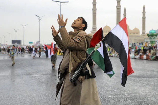 An armed demonstrator lifting a Palestinian and Yemeni flags gestures during an anti-Israel and anti-US rally in the Huthi-controlled capital Sanaa on January 19, 2024, protesting the US designation of Yemen's Huthi rebels as “terrorists”, after a series of attacks on Red Sea shipping amid ongoing battles between Israel and the militant Hamas group in Gaza. (Photo by Mohammed Huwais/AFP Photo)