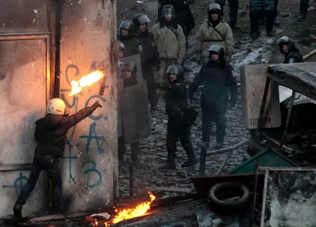 A protester throws a burning bottle during clashes with police, in central Kiev, Ukraine, Monday, January 20, 2014. (Photo by Sergei Chuzavkov/AP Photo)