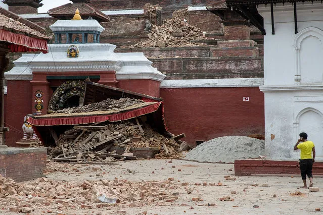 A young man speaks on the phone in front of a collapsed temple in the city center following an earthquake on April 25, 2015 in Kathmandu, Nepal. (Photo by Omar Havana/Getty Images)