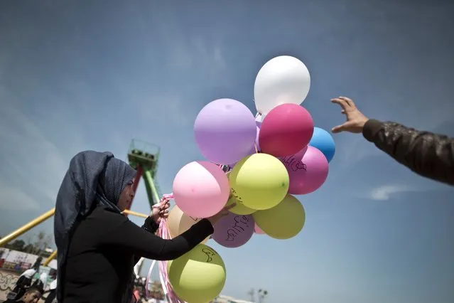 A Palestinian woman holds balloons, some reading in Arabic “women's rights”, during an event organised by the United Nations to mark the international women's day on March 8, 2016 at a park in Gaza City. (Photo by Mahmud Hams/AFP Photo)