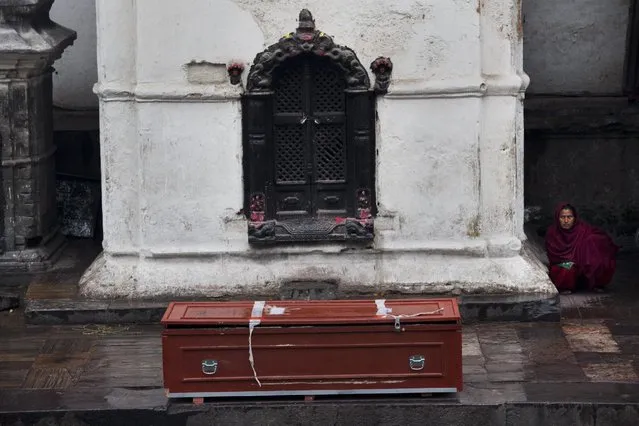 A woman sits near an empty coffin at the Pashupatinath temple on the banks of the Bagmati River in Kathmandu, Nepal, Tuesday, April 28, 2015. (Photo by Bernat Armangue/AP Photo)