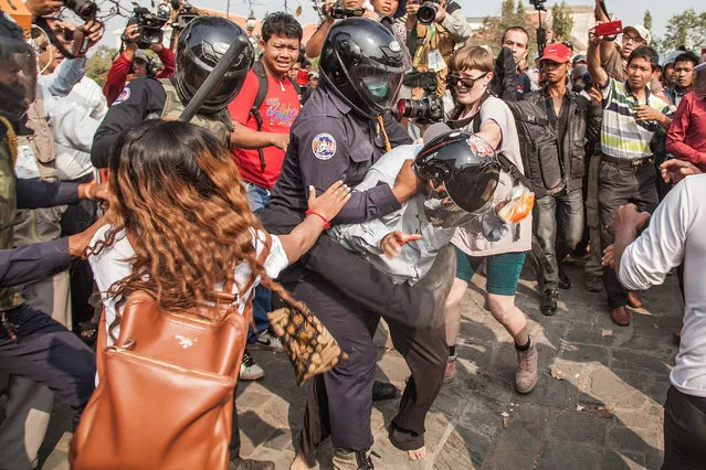 A member of the municipal security forces hits a protester as demonstrators and security forces clash during a demonstration to re-take the opposition's base, Freedom Park, on January 26, 2014 in Phnom Penh, Cambodia. (Photo by Omar Havana/Getty Images)