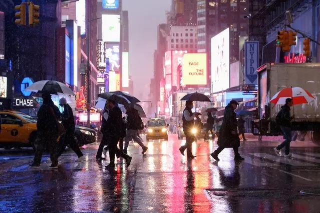 People hold umbrellas while crossing the street during a nor'easter in New York, U.S. October 26, 2021. (Photo by Caitlin Ochs/Reuters)