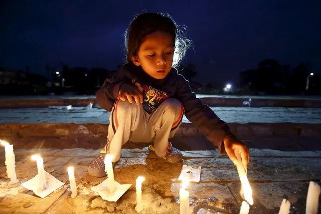 A boy lights a candle during a candle light vigil to remember the victims of last week's earthquake in Kathmandu, Nepal 2 May 2015. (Photo by Navesh Chitrakar/Reuters)