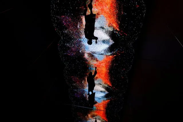 A visitor stands in front of an immersive art installation titled “Machine Hallucinations – Space: Metaverse” by media artist Refik Anadol, which will be converted into NFT and auctioned online at Sotheby's, at the Digital Art Fair, in Hong Kong, China on September 30, 2021. (Photo by Tyrone Siu/Reuters)