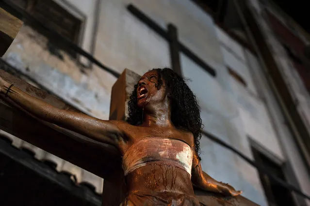 In this April 19, 2019 photo, a woman plays one of the two thieves crucified with Jesus during the reenactment of the Passion of Christ on Good Friday during Holy Week at the Rocinha slum in Rio de Janeiro, Brazil. Residents who organized, acted and directed the play have translated it to reflect the scenery and realities around them. They say the themes of violence, persecution and injustice resonate with their lives. (Photo by C.H. Gardiner/AP Photo)