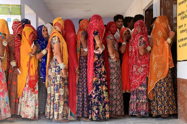 Indian voters stand in a queue to cast their vote at a polling station for the fourth phase of India's general elections in the outskirts of Ajmer, in the Indian state of Rajasthan, on April 29, 2019. Voting began for the fourth phase of India's general parliamentary elections as Indians exercise their franchise in the country's marathon election which started on April 11 and runs through to May 19 with the results to be declared on May 23. (Photo by Himanshu Sharma/AFP Photo)