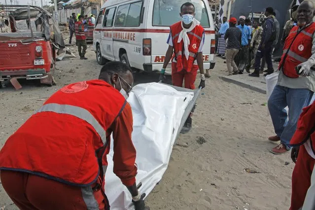 Rescue workers carry away the body of a civilian who was killed in a blast in Mogadishu, Somalia Thursday, November 25, 2021. Witnesses say a large explosion has occurred in a busy part of Somalia's capital during the morning rush hour. (Photo by Farah Abdi Warsameh/AP Photo)