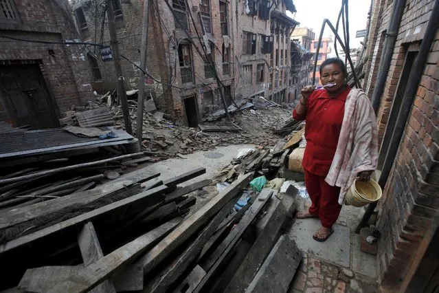 A Nepalese woman brushes her teeth next to quake damaged houses in Bhaktapur, Nepal, Thursday, May 14, 2015. (Photo by Bikram Rai/AP Photo)