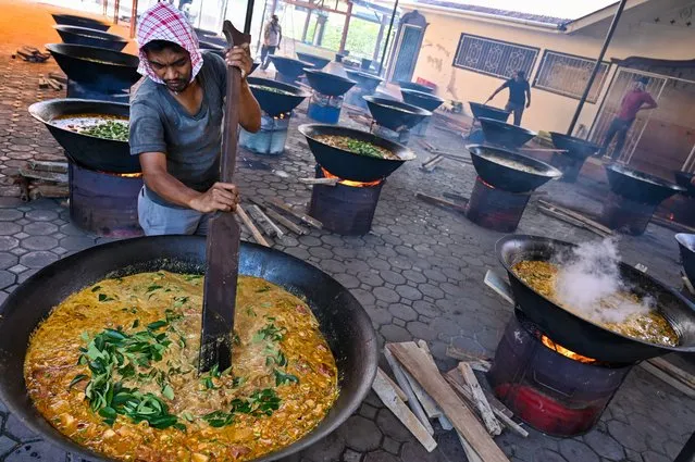 A man cooks traditional curry dishes called 'kuah beulangong' in cauldrons to be shared at iftar, the breaking of fast, during the Muslim holy month of Ramadan in Banda Aceh on April 2, 2024. (Photo by Chaideer Mahyuddin/AFP Photo)