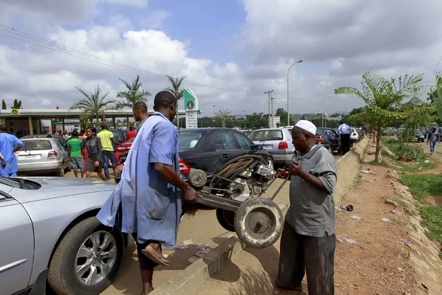 Men who work as tyre vulcanizers carry a piece of equipment across a road packed with vehicles waiting outside a petrol station of state-owned energy company Nigerian National Petroleum Corporation (NNPC) in Abuja, Nigeria May 25, 2015. (Photo by Afolabi Sotunde/Reuters)
