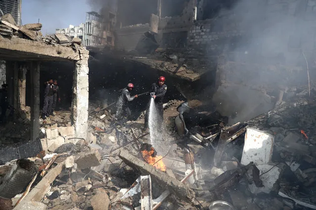 Syrian men and Civil Defence volunteers, also known as the White Helmets, extinguish fire following reported government airstrike on the rebel-held town of Douma, on the eastern outskirts of the capital Damascus, on February 26, 2017. Government raids continue despite the United Nations confirmation a few days earlier that Moscow formally asked its ally Damascus to stop launching strikes during the Geneva negotiations, which began earlier in the week. (Photo by Abd Doumany/AFP Photo)