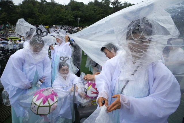 Buddhists cover themselves and their lamps with plastic sheets as they prepare for a lantern parade ahead of the upcoming birthday of Buddha at Dongguk University in Seoul, South Korea, Saturday, May 11, 2024. (Photo by Ahn Young-joon/AP Photo)