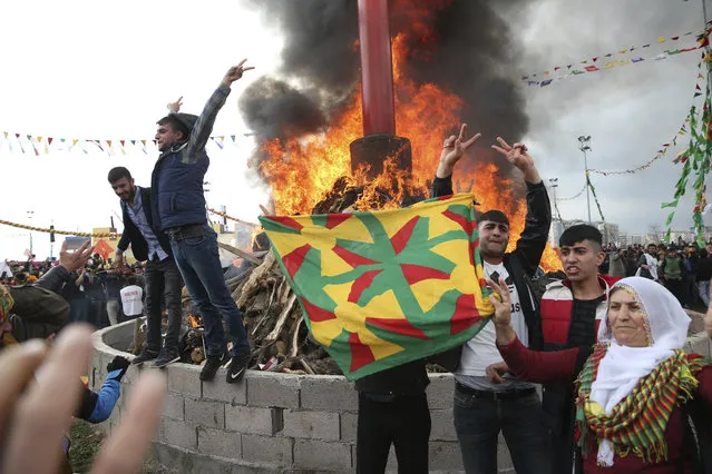 People gather around a bonfire after Turkish authorities permitted the Newroz celebration, in Diyarbakir, Turkey, Tuesday, March 21, 2017. Thousands celebrated the Newroz festival in Istanbul and in Diyarbakir, a mainly Kurdish city in a region where Kurdish militants regularly clash with government forces. Many flags proclaimed  “No” in the Turkish and Kurdish languages, referring to President Recep Tayyip Erdogan’s bid to gain more power for his office in an April 16 referendum. (Photo by Lefteris Pitarakis/AP Photo)