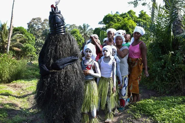 Secret Bondo society members are led by the Black Devil as they begin their procession across the field of Songo village in order to perform on December 2, 2018. The three young girls wearing white face paint symbolise those that are awaiting future initiation. (Photo by Lynn Rossi/AFP Photo)