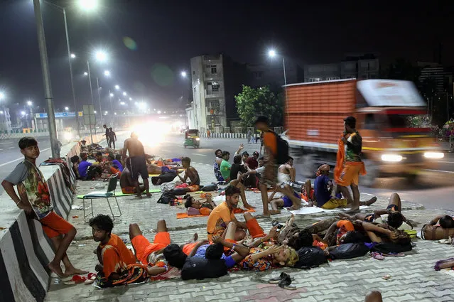 Indian devotees of Lord Shiva (one of the most powerful and revered deities in Hinduism) resting under a flyover near the Akshardham temple in New Delhi, India 29 July 2019. Kanwar Yatra is an annual pilgrimage of devotees of Shiva. Millions of participants gather sacred water from the Ganga and carry it across hundreds of miles to dispense as offerings in their local Shiva shrines, or specific temples such as Pura Mahadeva and Augharnath temple in Meerut, and Kashi Vishwanath, Baidyanath, and Deoghar in Jharkhand. (Photo by Harish Tyagi/EPA/EFE)