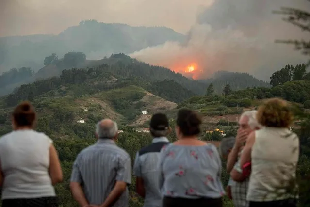 Residents observe smoke billowing from a forest fire raging near Montana Alta on the island of Gran Canaria on August 18, 2019. Authorities on the Spanish island of Gran Canaria evacuated residents as a forest fire broke out just days after another blaze raged in the same area. (Photo by Desiree Martin/AFP Photo)