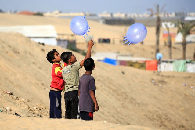 Displaced Palestinian children play with surgical rubber gloves in Rafah in the southern Gaza Strip, on May 31, 2024, amid the ongoing conflict between Israel and the Palestinian Hamas group. (Photo by Eyad Baba/AFP Photo)