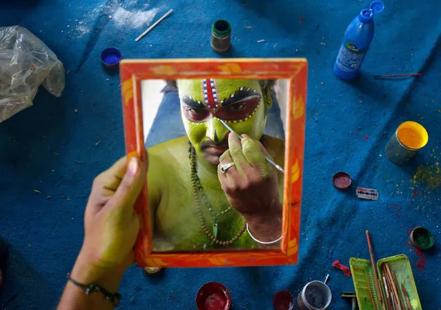 An artiste is reflected in a mirror as he applies make-up backstage before taking part in a celebration to mark Hindu festival of Ramnavami inside the premises of a temple in Bengaluru, India April 5, 2017. (Photo by Abhishek N. Chinnappa/Reuters)