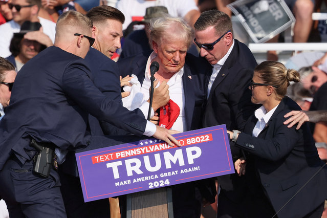 Republican presidential candidate and former President Donald Trump is assisted by security personnel after gunfire rang out during a campaign rally at the Butler Farm Show in Butler, Pennsylvania on July 13, 2024. (Photo by Brendan McDermid/Reuters)