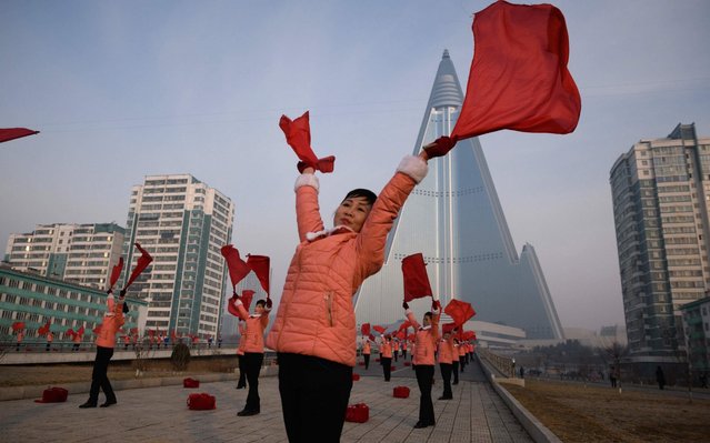 Members of a Socialist Women's Union propaganda troupe perform a dance and music routine in front of the Ryugyong hotel in Pyongyang on March 9, 2019. All non-working North Korean women are members of the Socialist Women's Union, whose propaganda troupes are a familiar fixture performing flag-waving and drum routines at intersections and landmarks around Pyongyang during the morning rush-hour period. (Photo by Ed Jones/AFP Photo)