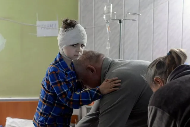 Misha, 5, who lost his mother some weeks ago and got injured during a Russian strike, is helped by his grand father to dress up in the basement of a hospital on March 26, 2022, in Mykolaiv. (Photo by Bulent Kilic/AFP Photo)