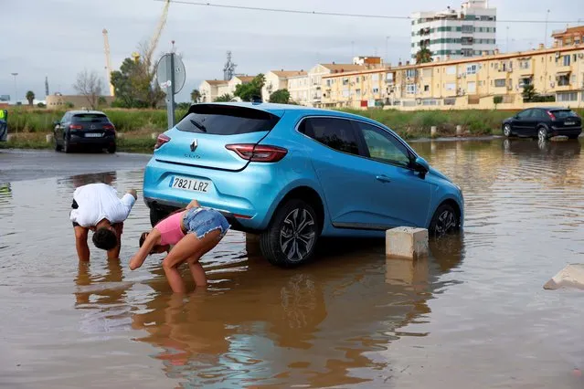 A couple inspect a damaged car is seen after flooding in Sagunto, Valencia, Spain, 30 August 2021. A total of 180 liters per squ​are meter have been registered in the town during heavy rains overnight. (Photo by Biel Aliño/EPA/EFE)