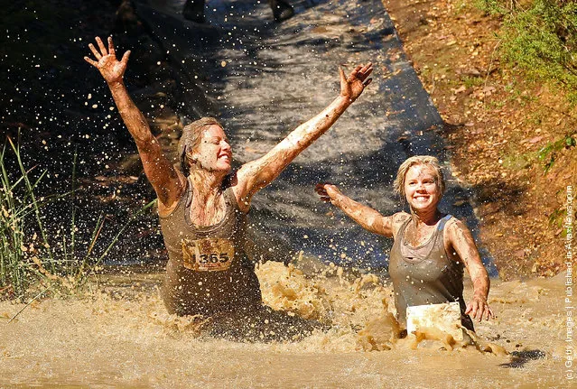 Competitors fall into muddy water as they compete in The Tough Bloke Challenge in Melbourne, Australia