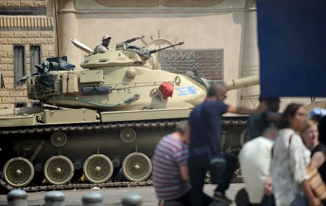 A soldier inside a tank stands guard outside Tora prison while journalists wait to enter a court in Cairo, Egypt, August 2, 2015. An Egyptian court on Sunday postponed for the second time the verdict in the retrial of Al Jazeera television journalists who have been charged with aiding a terrorist organisation, a reference to the banned Muslim Brotherhood, to August 29. (Photo by Shadi Bushra/Reuters)