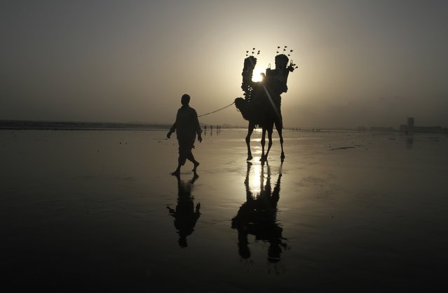 A Pakistani family enjoy a camel ride at the Karachi beach, in Pakistan, Tuesday, August 4, 2015 in Pakistan. (Photo by Fareed Khan/AP Photo)