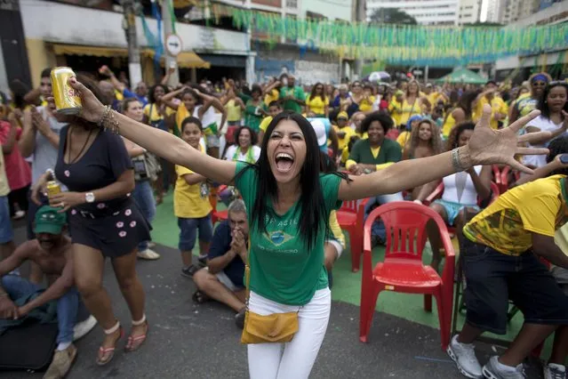 Brazil soccer fans celebrate after their team scored a penalty shot against Chile as they watch the World Cup round of 16 match on TV outside the Vai Vai Samba school in Sao Paulo, Brazil, Saturday, June 28, 2014. Brazil won 3-2 on penalties. (Photo by Dario Lopez-Mills/AP Photo)