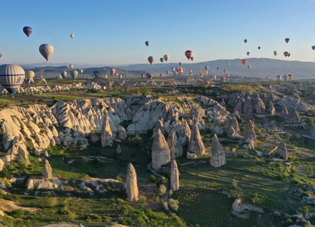 Hot-air balloons glide over fairy chimneys in the Cappadocia region, located in Nevsehir province, Turkiye on May 09, 2022. Cappadocia on the UNESCO World Heritage List receives tourists from various countries, when suitable weather conditions, it reaches three thousand tourists participated in hot air balloon tours daily. (Photo by Behcet Alkan/Anadolu Agency via Getty Images)