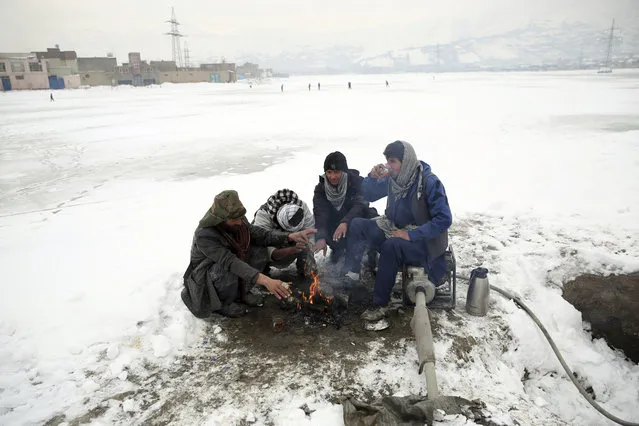 People sit around a fire to warm themselves after a heavy snowfall in Kabul, Afghanistan, Tuesday, January 14, 2020. Severe winter weather has struck parts of Afghanistan and Pakistan, with heavy snowfall, rains and flash floods that left dozens dead, officials said Monday as authorities struggled to clear and reopen highways and evacuate people to safer places. (Photo by Rahmat Gul/AP Photo)