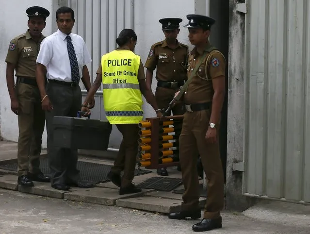 A police scene of crime officer carries equipment into a cemetery after the Colombo Additional Magistrate allowed the exhumation of the body of rugby player Wasim Thajudeen in Colombo August 10, 2015. According to initial reports, Thajudeen's body was found in a burnt-out car wreck and his death was ruled an accident. But police last month requested that the case be reopened after saying they have uncovered new evidence, local media reported. (Photo by Dinuka Liyanawatte/Reuters)