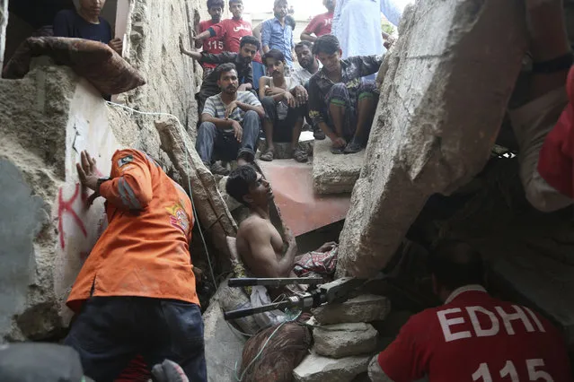 Pakistani volunteers try to rescue a trapped resident in Karachi, Pakistan, Tuesday, July 18, 2017. A dilapidated, three-story building in a poorer neighborhood of Pakistan's sprawling port city of Karachi collapsed as the residents slept. (Photo by Shakil Adil/AP Photo)