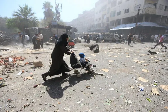 A woman pushes a baby stroller as she rushes away after what activists said were airstrikes by forces loyal to Syria's President Bashar al-Assad on a busy marketplace in the Douma neighborhood of Damascus, Syria August 12, 2015. (Photo by Bassam Khabieh/Reuters)