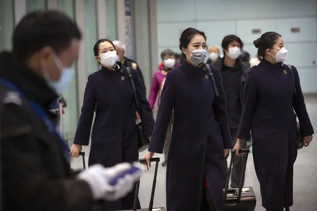 Flight crew members wearing face masks walk through the international arrivals area at Beijing Capital International Airport in Beijing, Thursday, January 30, 2020. China counted 170 deaths from a new virus Thursday and more countries reported infections, including some spread locally, as foreign evacuees from China's worst-hit region returned home to medical observation and even isolation. (Photo by Mark Schiefelbein/AP Photo)